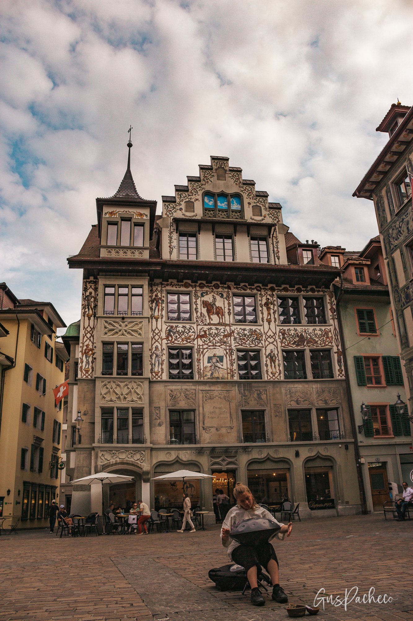 Hirschenplatz square with ornate murals and a street musician in Lucerne